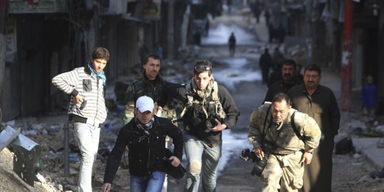 Varios periodistas corren en una calle de Alepo, Siria.