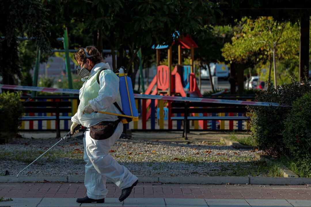 Una trabajadora municipal desinfecta las proximidades un parque infantil clausurado en la localidad madrileña de Alcobendas