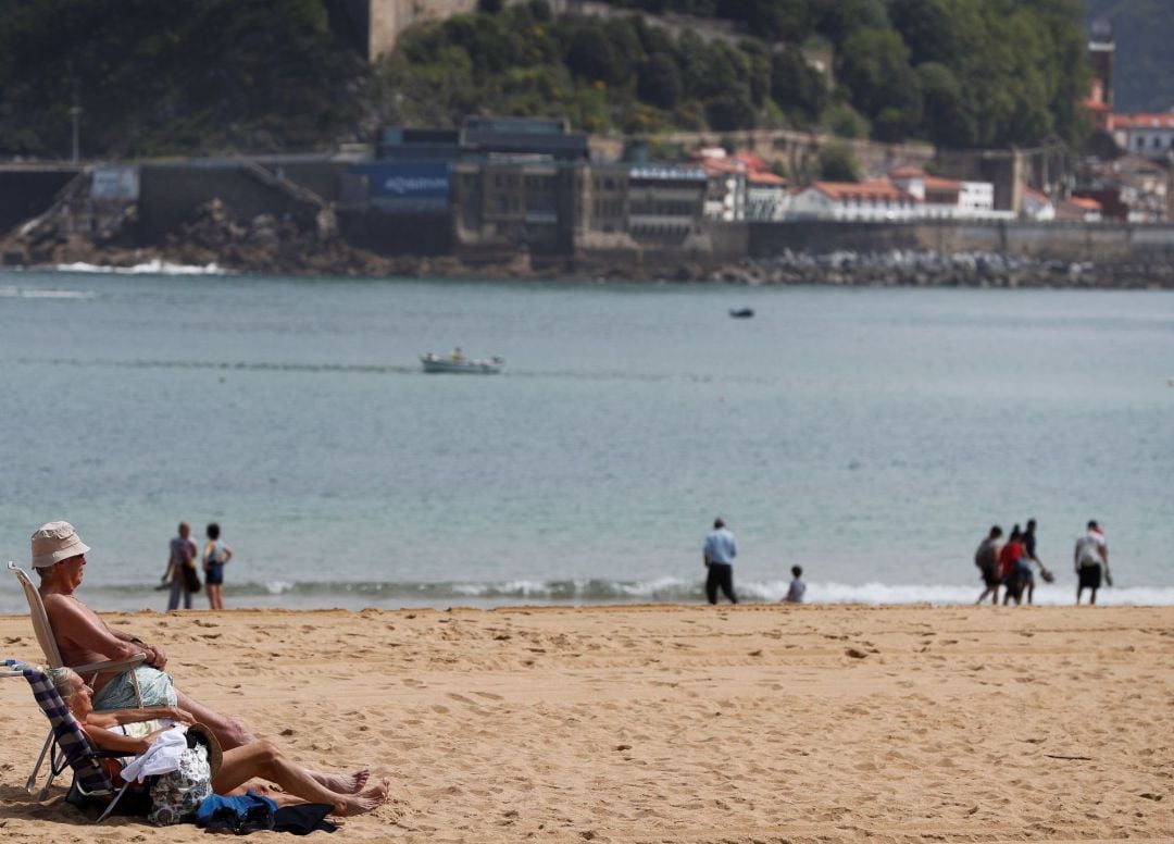 Una pareja toma el sol en la playa de Ondarreta.