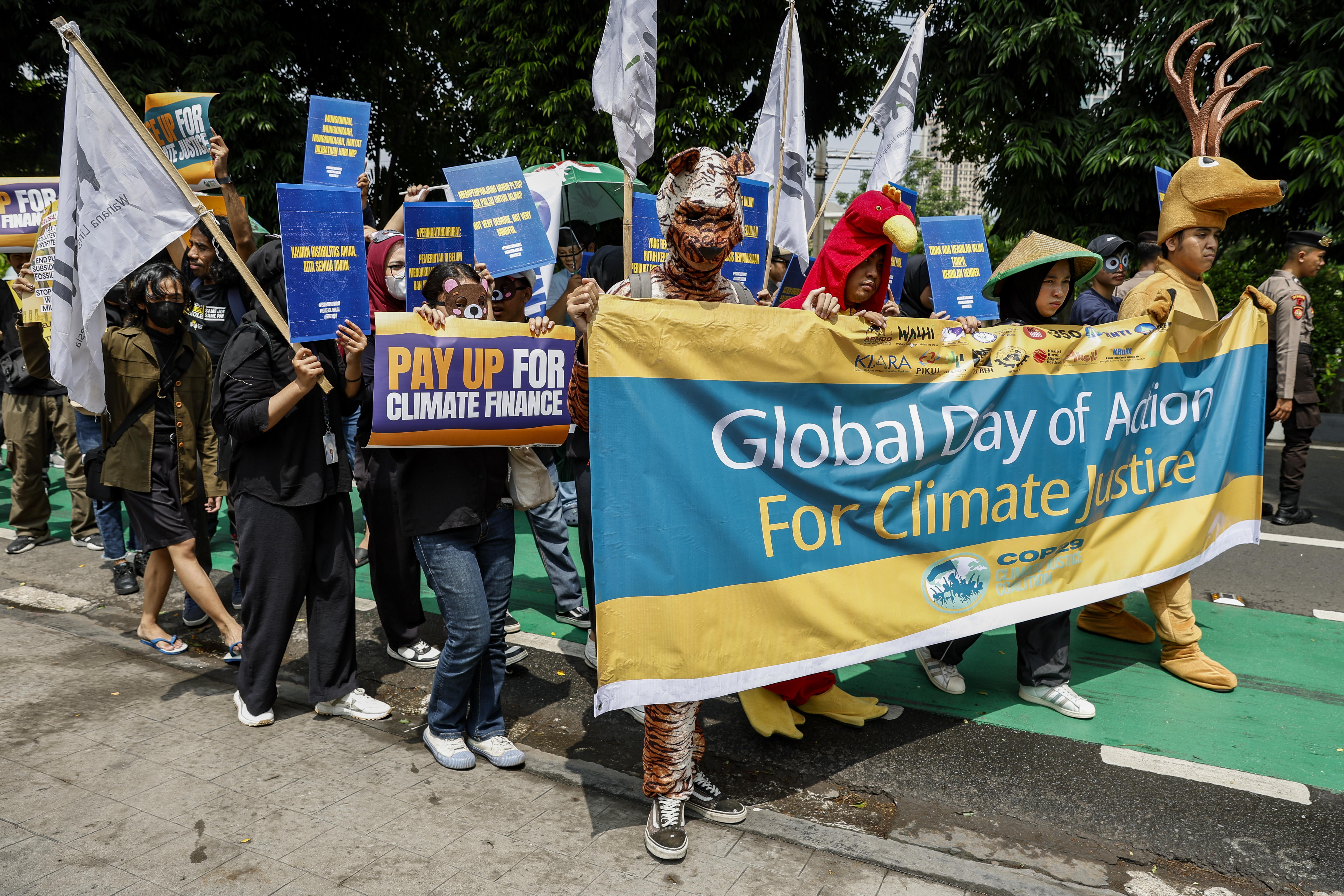 Activistas ambientales sostienen carteles y pancartas mientras marchan frente al edificio del Ministerio de Medio Ambiente durante una manifestación como parte del día de acción mundial por la justicia climática en Yakarta, Indonesia