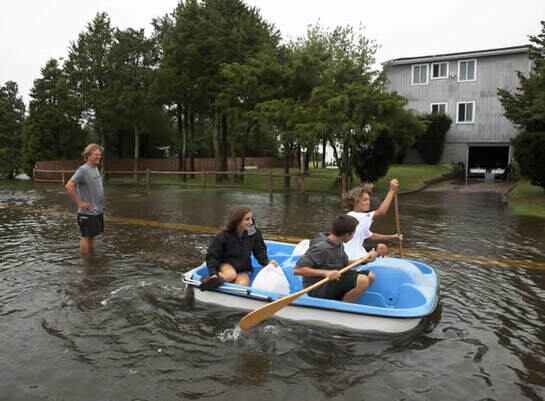 Unos vecinos del barrio de Southampton, en Nueva York, navegan por la calle inundada para llegar a sus casas