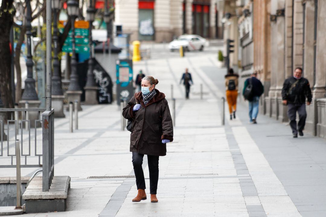 Una mujer con mascarilla pasea por la calle de Alcalá durante el primer día de la cuarta semana de estado de alarma decretado por el Gobierno para combatir el coronavirus, en Madrid