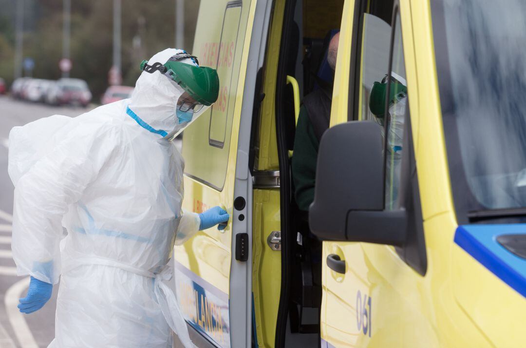 Un trabajador sanitario totalmente protegido cierra la puerta de una ambulancia tras recoger a un anciano de la residencia de ancianos de San Cibrao.