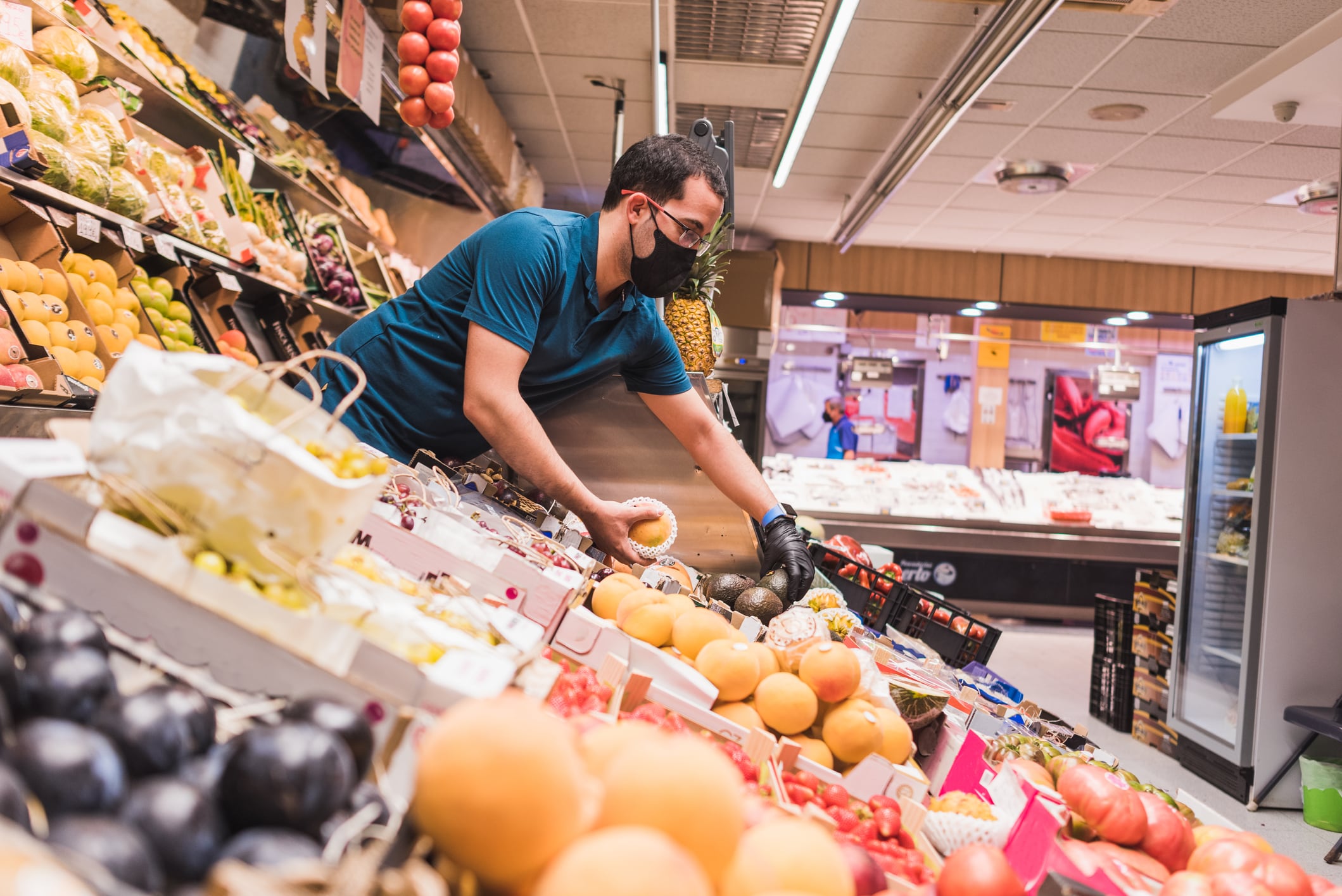 Un trabajador selecciona varias frutas en su frutería.