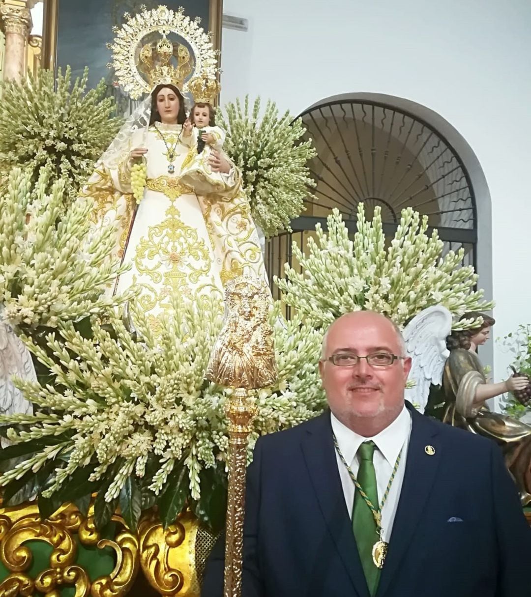 El presidente de la Hermandad posa con al patrona de fondo