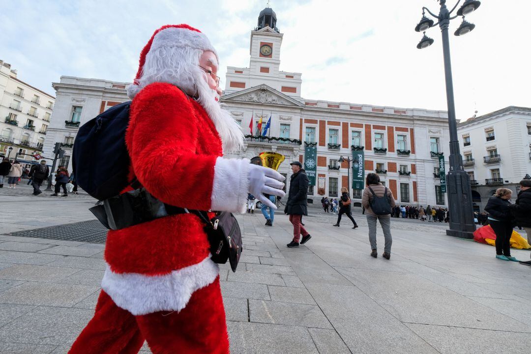 Un hombre disfrazado de Papá Noel frente a la Casa de Correos (actual sede del Gobierno de la Comunidad de Madrid), en la Plaza del Sol de Madrid.