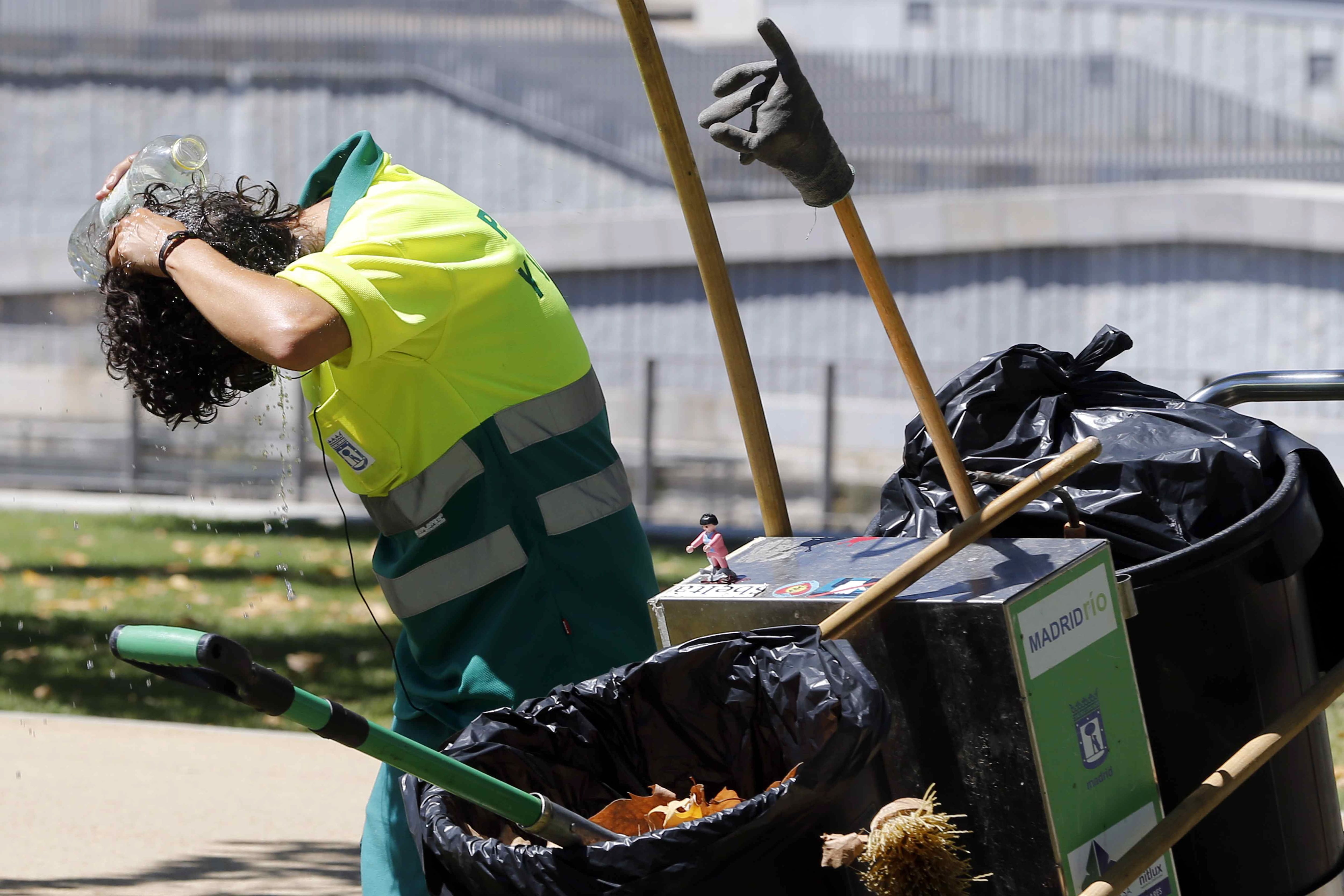 Una trabajadora del servicio de limpieza municipal se refresca en las inmediaciones del parque de Madrid Río