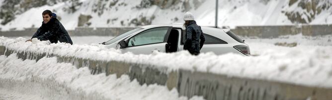 Varias personas disfrutan de la nieve junto a una carretera de Navacerrada (Madrid)