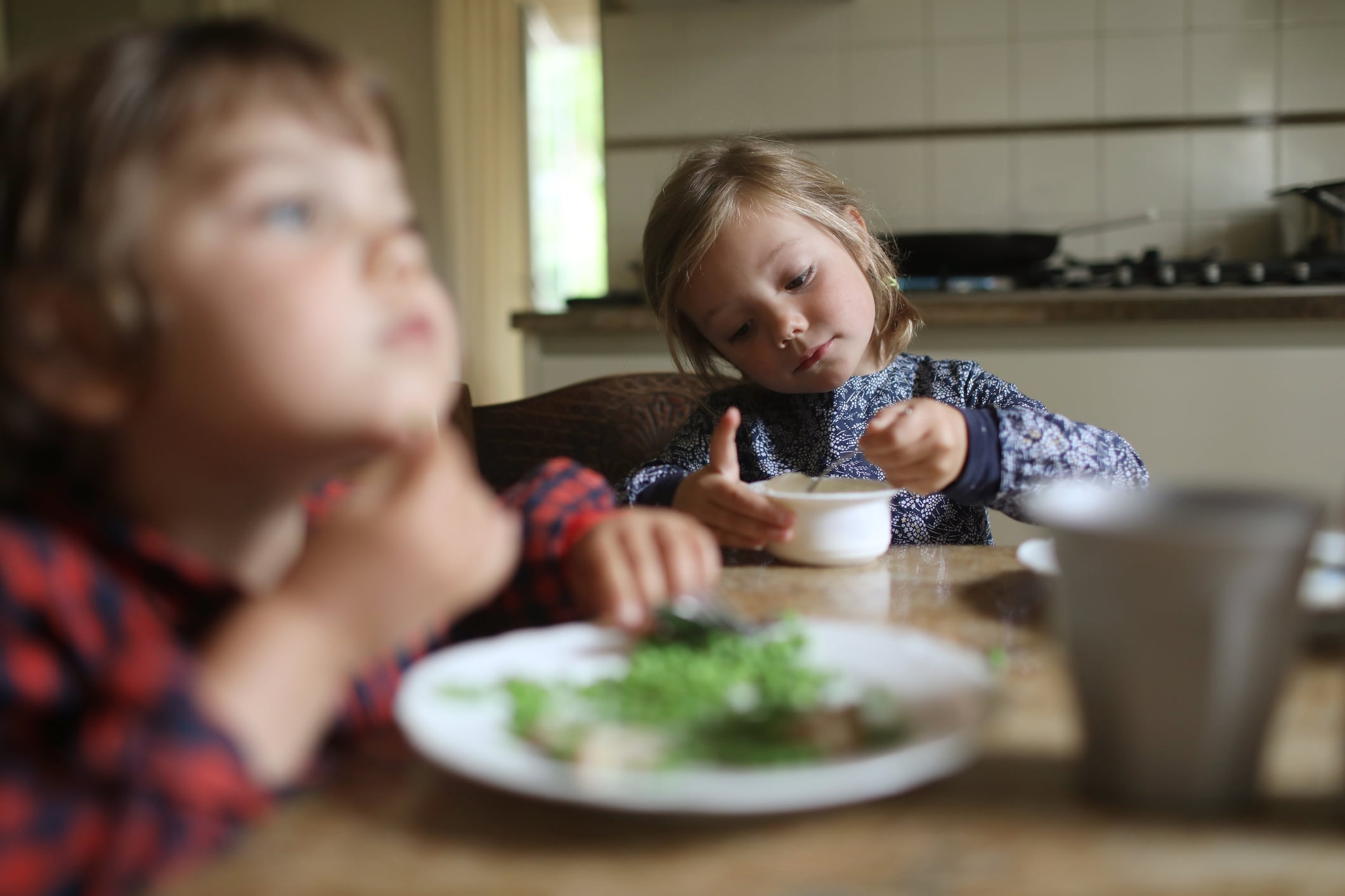 Dos hermanos, comiendo en la cocina de su casa.