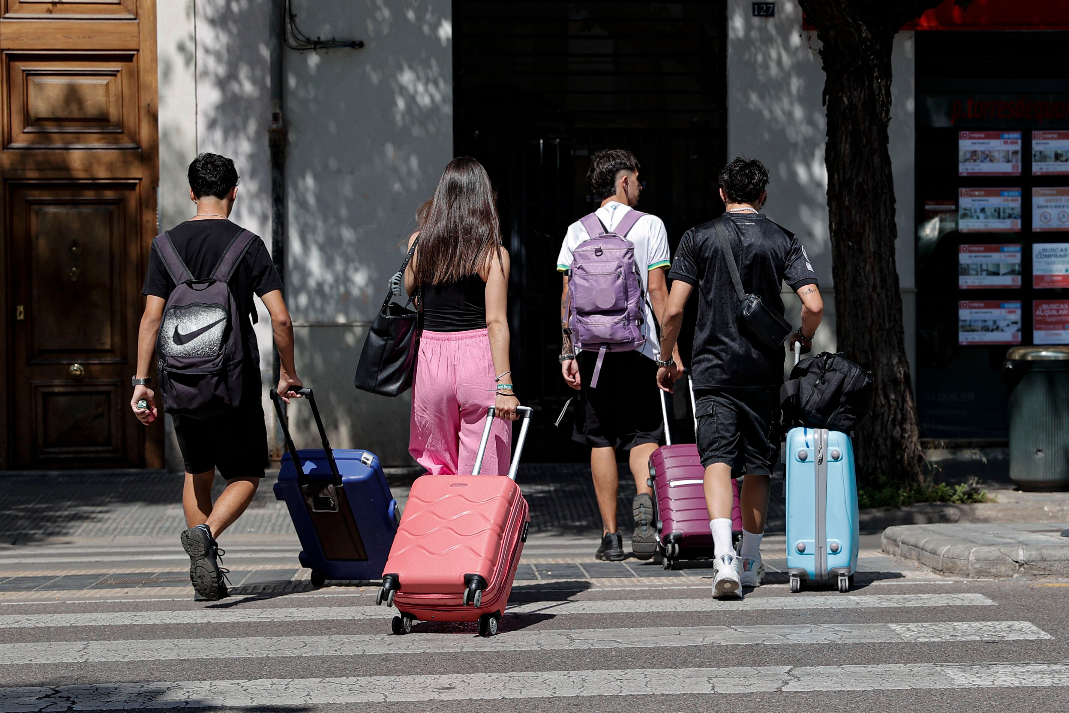 Un grupo de jóvenes acarrea sus maletas por una calle de València.