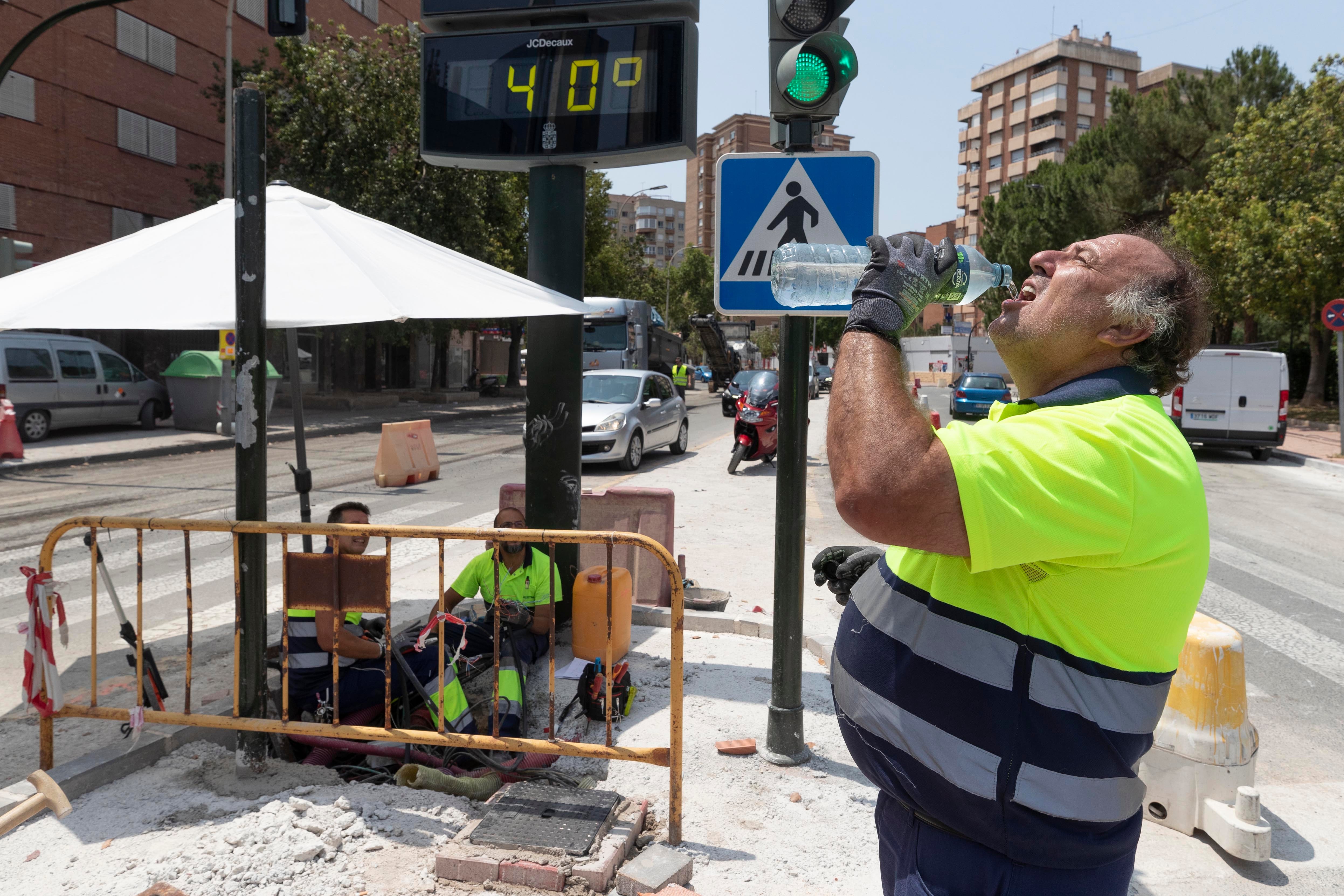 Un trabajador de la construcción combate el calor con agua junto a un termómetro que marca 40 grados este martes en la avenida de la Fama de Murcia. Archivo. EFE/Marcial Guillén