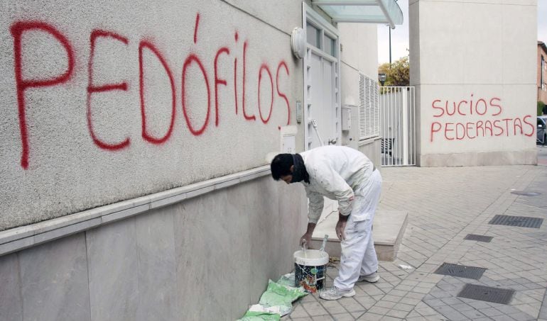 Un pintor comienza a repasar con pintura blanca una de las pintadas aparecidas en rojo esta mañana con acusaciones de pedofilia y pederastia en las paredes de la parroquia San Juan María Vianney de Granada