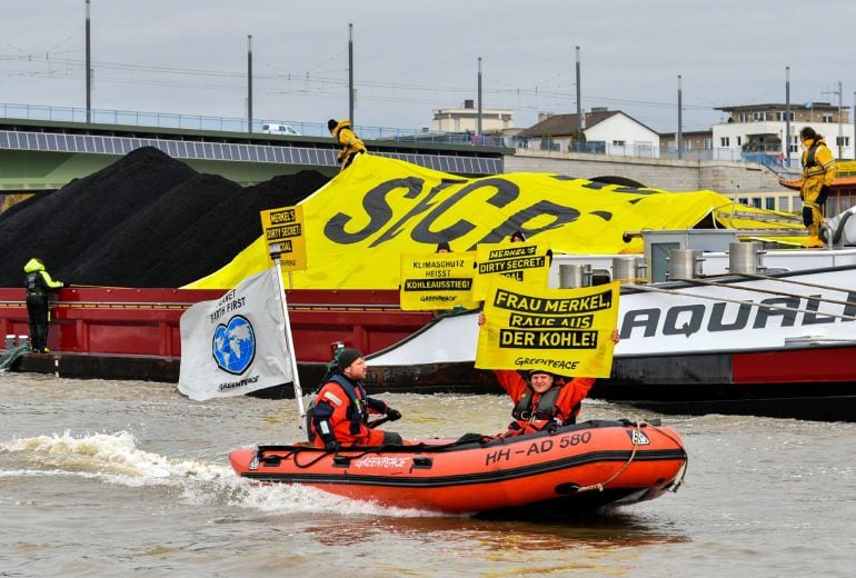 Varios activistas de Greenpeace pasan junto a un buque de carga de carbón a la vez que cubren el mineral con una gran pancarta durante una protesta en el río Rin en el ámbito de la cumbre del clima COP23 en Bonn (Alemania). 