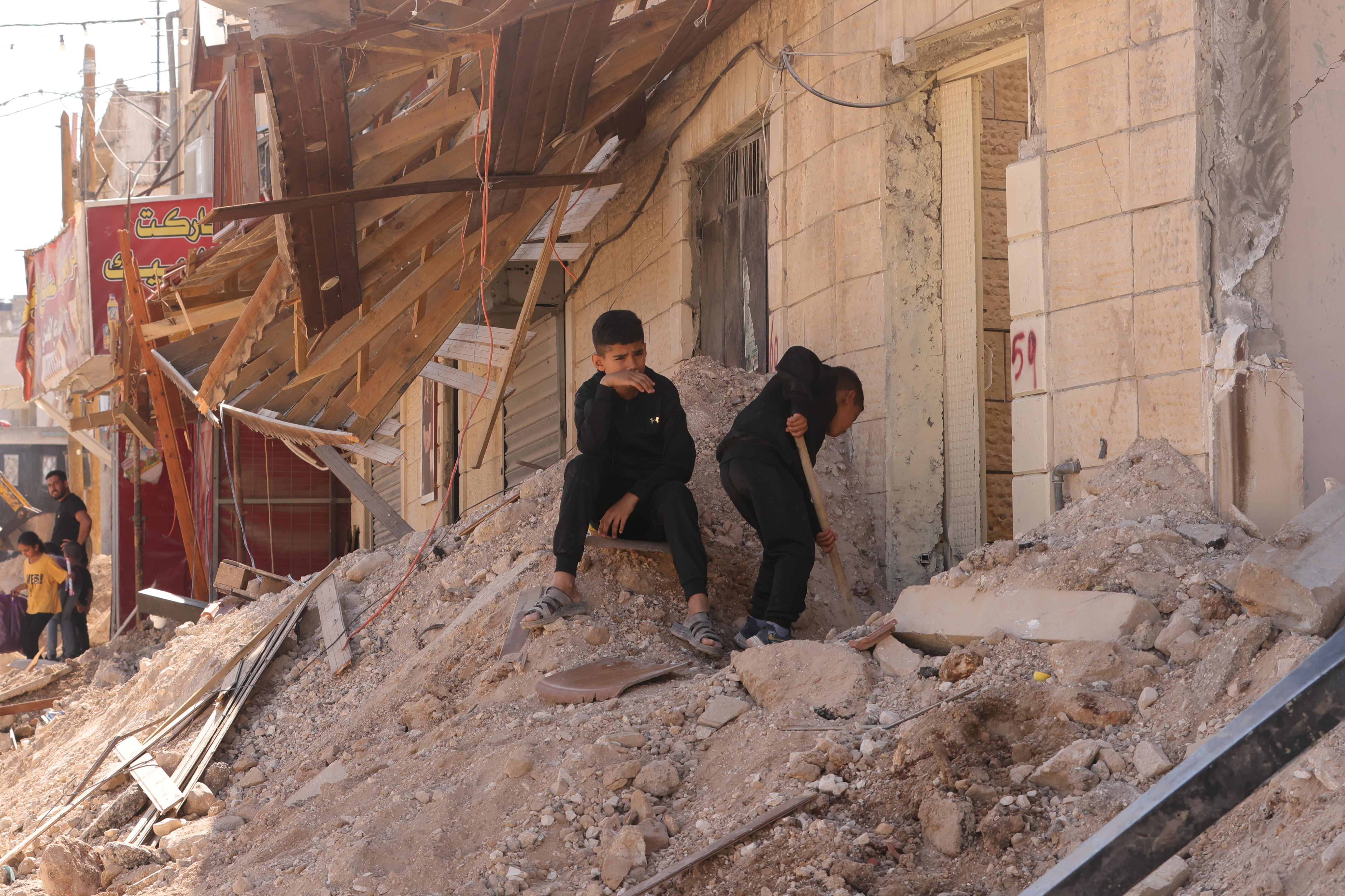 Dos niños palestinos inspeccionan los escombros de un edificio dañado un día después de una incursión israelí en la ciudad de Jenín, en Cisjordania