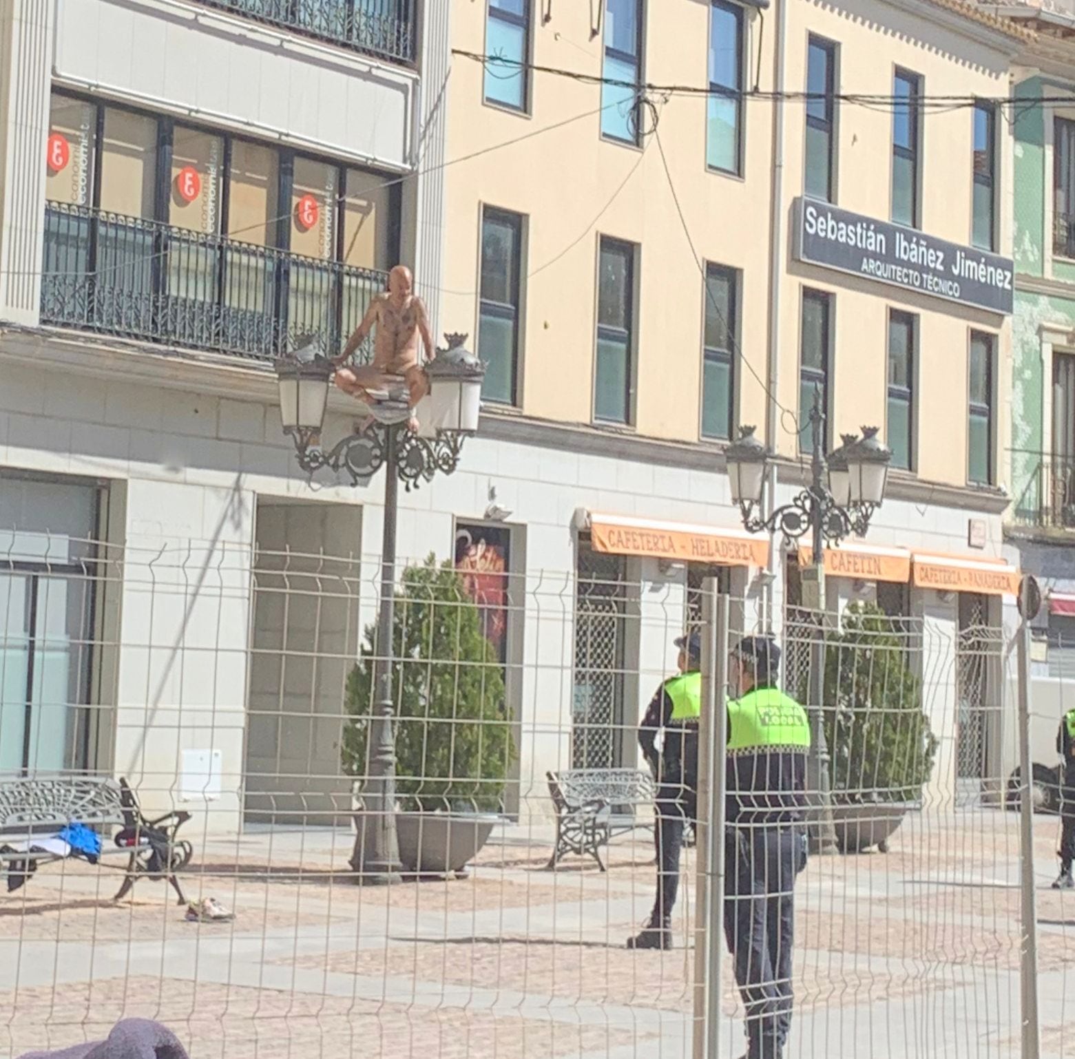 El hombre subido a una farola desnudo