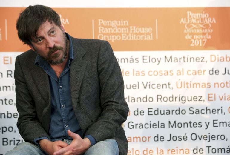 Fotografía facilitada por Alfaguara del escritor madrileño Ray Loriga, que posa junto al cartel de la XX edición del Premio Alfaguara de novela