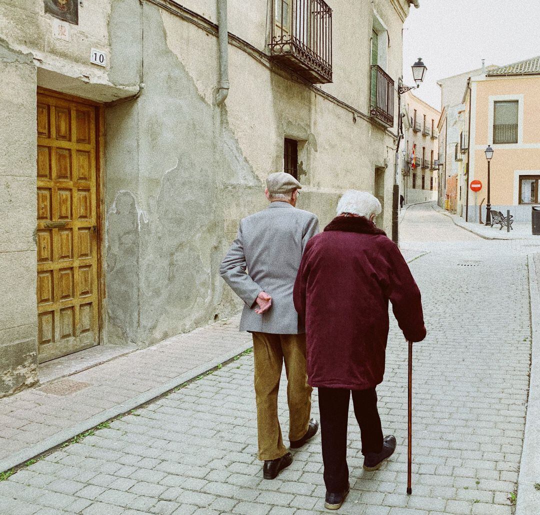 Dos ancianos pasean por la calle de un municipio