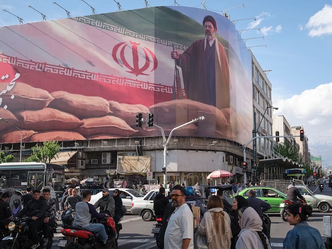 Un grupo de personas camina delante de un cártel del líder supremo de Irán Mojtaba Jameneí en el centro de Teherán pocas horas antes de que expire el alto el fuego entre Irán y Estados Unidos.