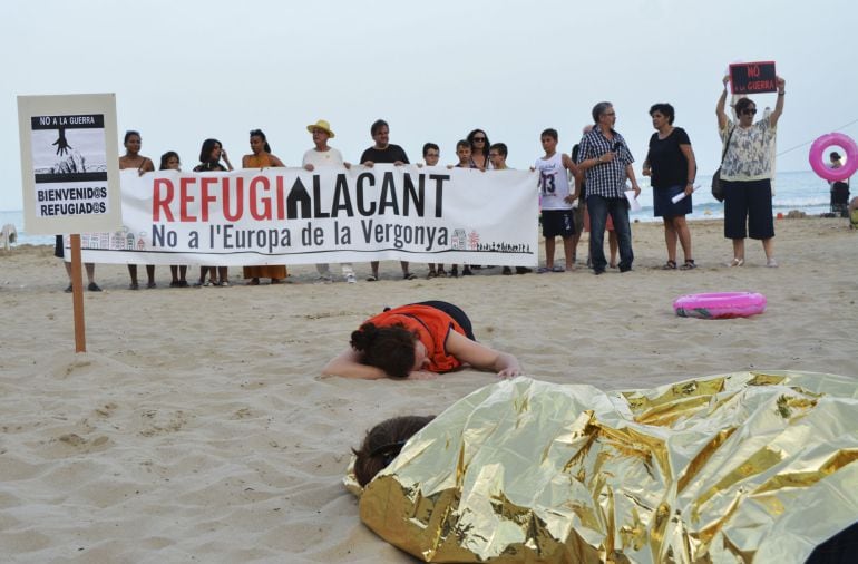 GRA463. ALICANTE, Tendidas sobre la arena, tapadas con mantas térmicas o con chalecos salvavidas, junto a una tienda de campaña y una hoguera, así han escenificado varias mujeres la realidad que están viviendo miles de refugiados en las zonas costeras del