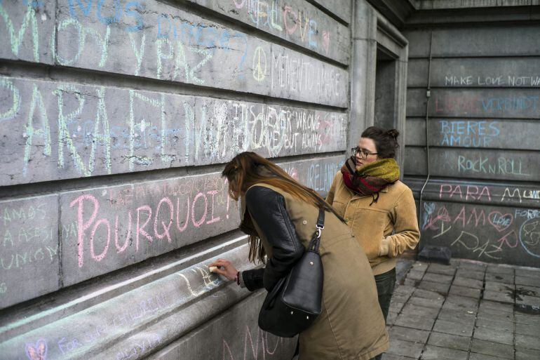 Una chica escribe un mensaje en recuerdo de las víctimas en un muro de la Plaza de la Bolsa de Bruselas (Bélgica). En la fotogalería, españoles atrapados en Bruselas.