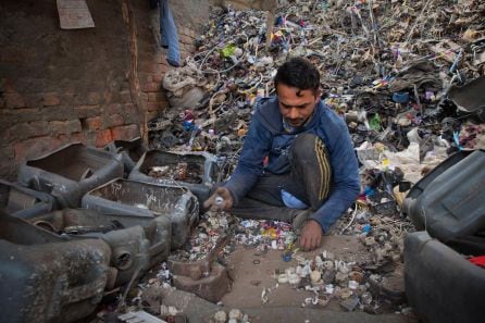 En Nueva Delhi (India) un trabajador recoge a mano pequeñas piezas de plástico para su posterior reciclaje.