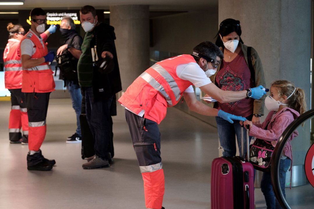 Personal de Cruz Roja toma la temperatura a los pasajeros procedentes de un vuelo