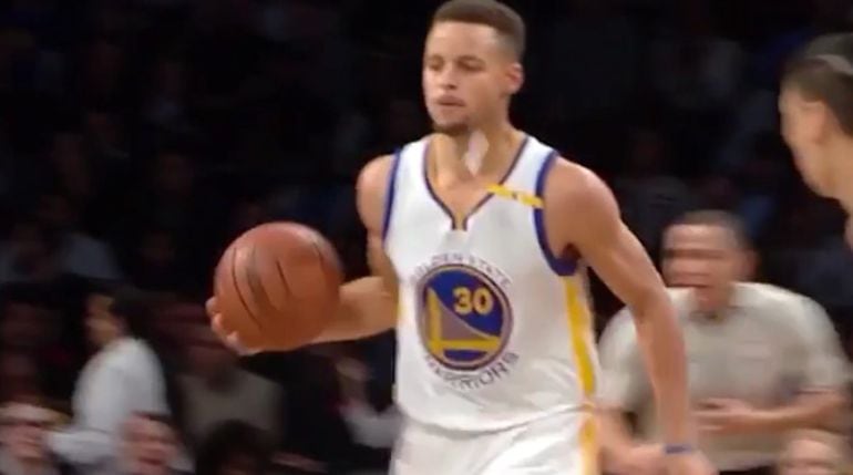 Curry se prepara para pasar el balón mientras algo se precipita delante de él