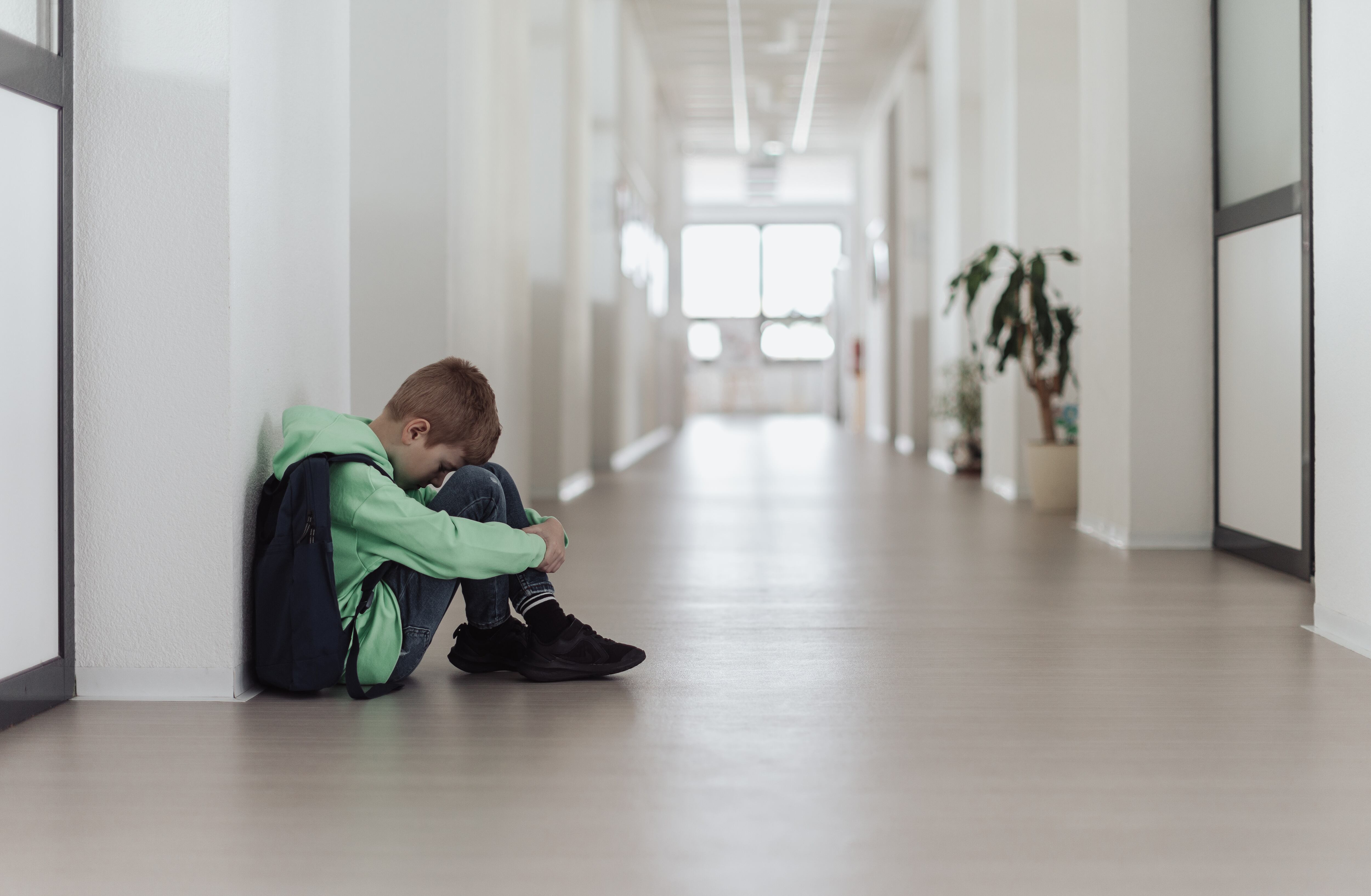 Un niño sentado en el pasillo de un centro educativo