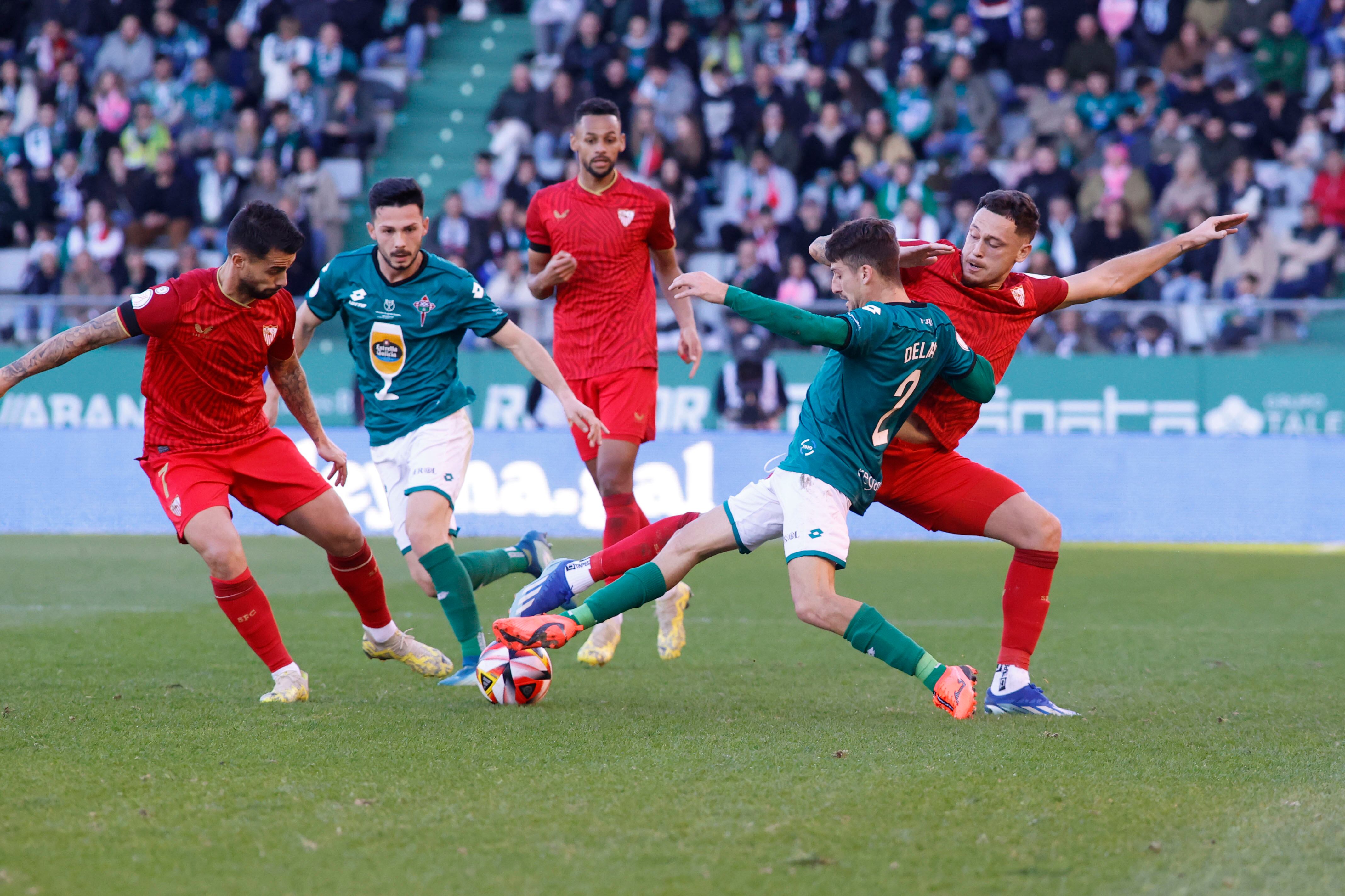 El defensa Julián Delmás (2d) del Racing Ferrol disputa un balón ante el delantero Lucas Ocampos (d) del Sevilla este domingo, durante un partido de dieciseisavos de final de la Copa del Rey, entre el Racing de Ferrol y el Sevilla, en el estadio de A Malata en Ferrol (Galicia).