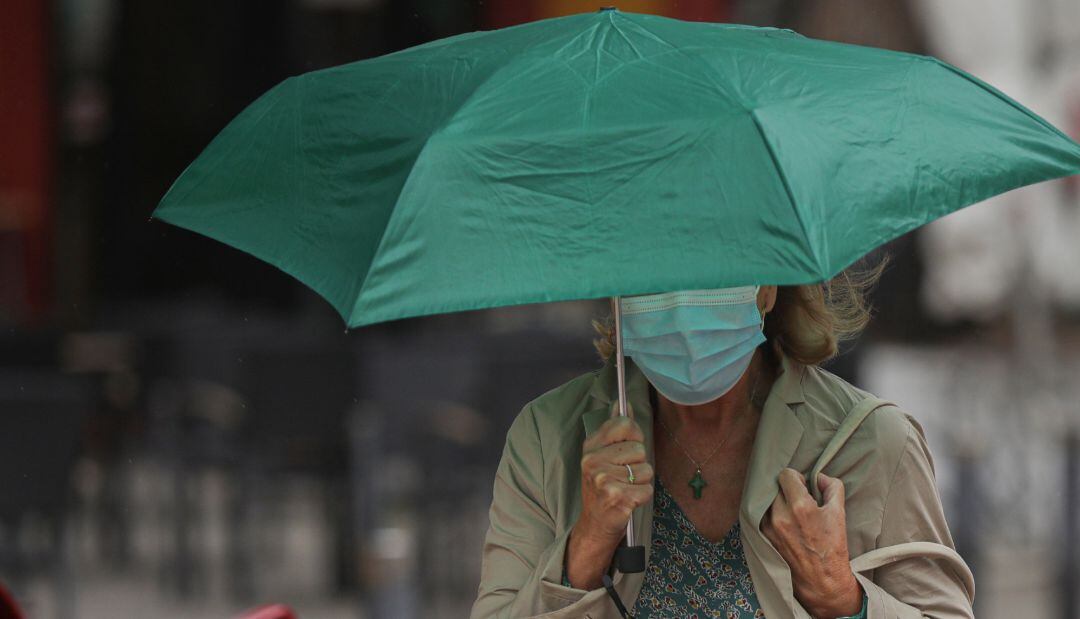 Una mujer se protege de la lluvia bajo un paraguas (Archivo)