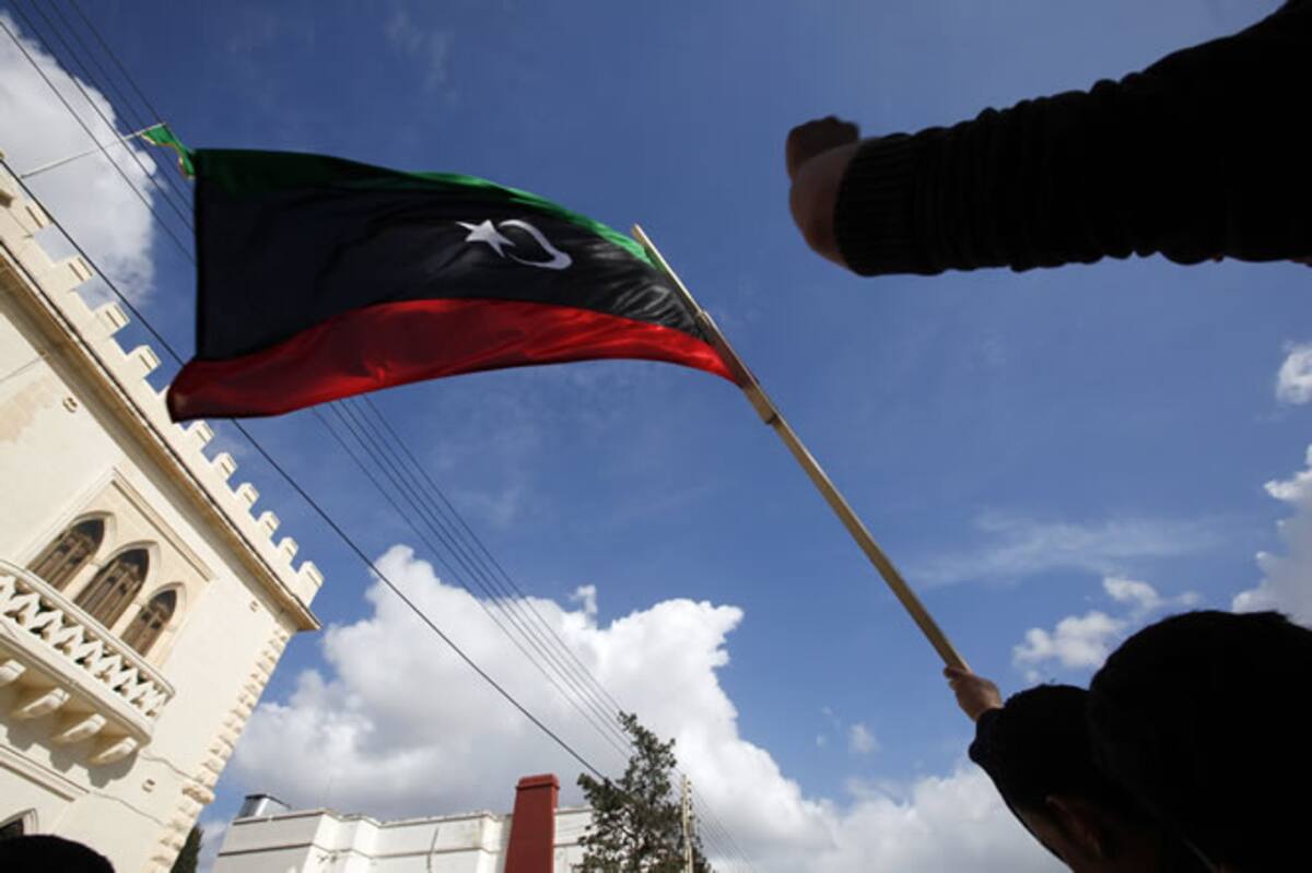 Los manifestantes sostienen una bandera de Libia durante la protesta en los alrededores de la embajada libanesa en Attard (Malta)