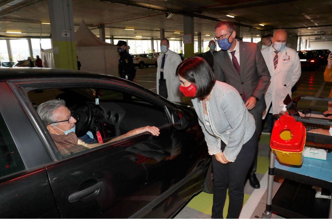 La Ministra de Sanidad conversa con una de las personas citadas para recibir su dosis en el punto de vacunación instalado en el aparcamiento del HUCA