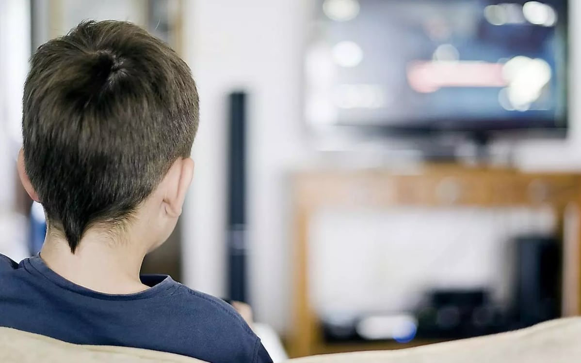 Un nen mira la televisió. A partir d'avui, Andorra Telecom incorpora nous canals a la fibra.