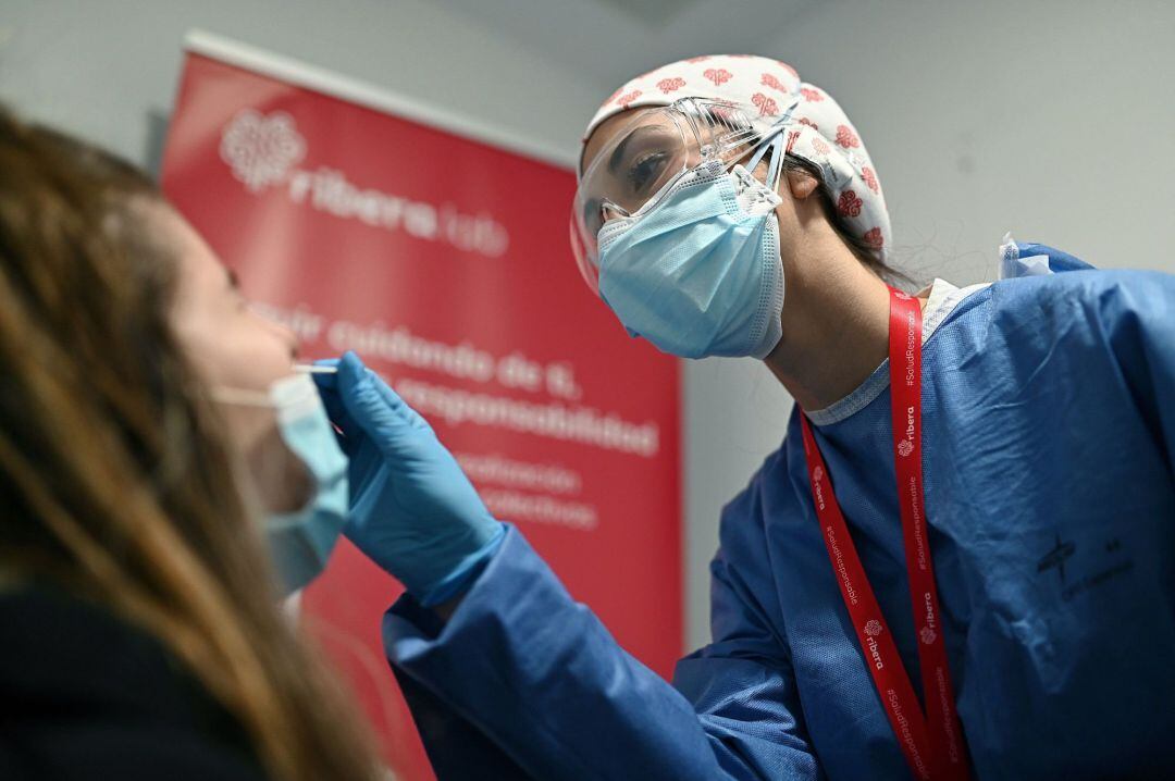 Una trabajadora sanitaria toma una muestra de saliva para un test de antígenos a una trabajadora en la estación de Atocha en Madrid, este lunes. La sanidad pública madrileña comenzará este lunes a realizar test de antígenos a personas que trabajan en las 