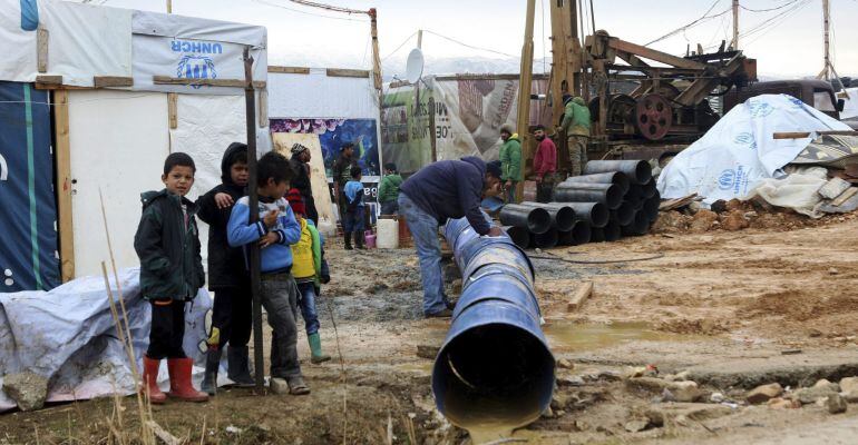 Varios niños ven como trabajan los adultos en el campo de refugiados sirios de Amriyeh en la localidad de Saadnayel al este de Líbano 