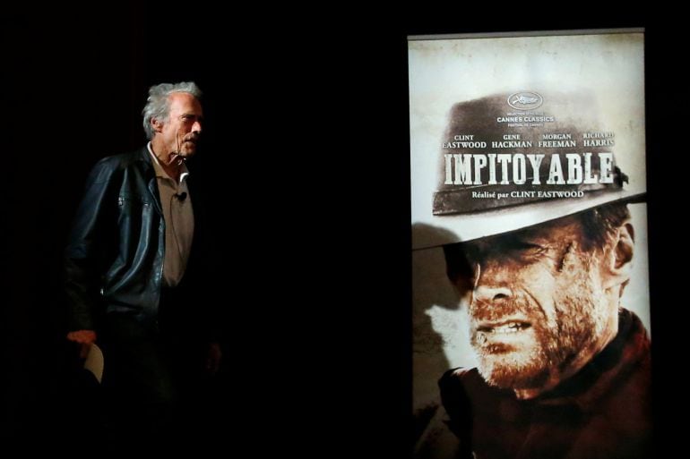 Director Clint Eastwood walks past a poster of his film &quot;Unforgiven&quot; (Impitoyable) as he arrives