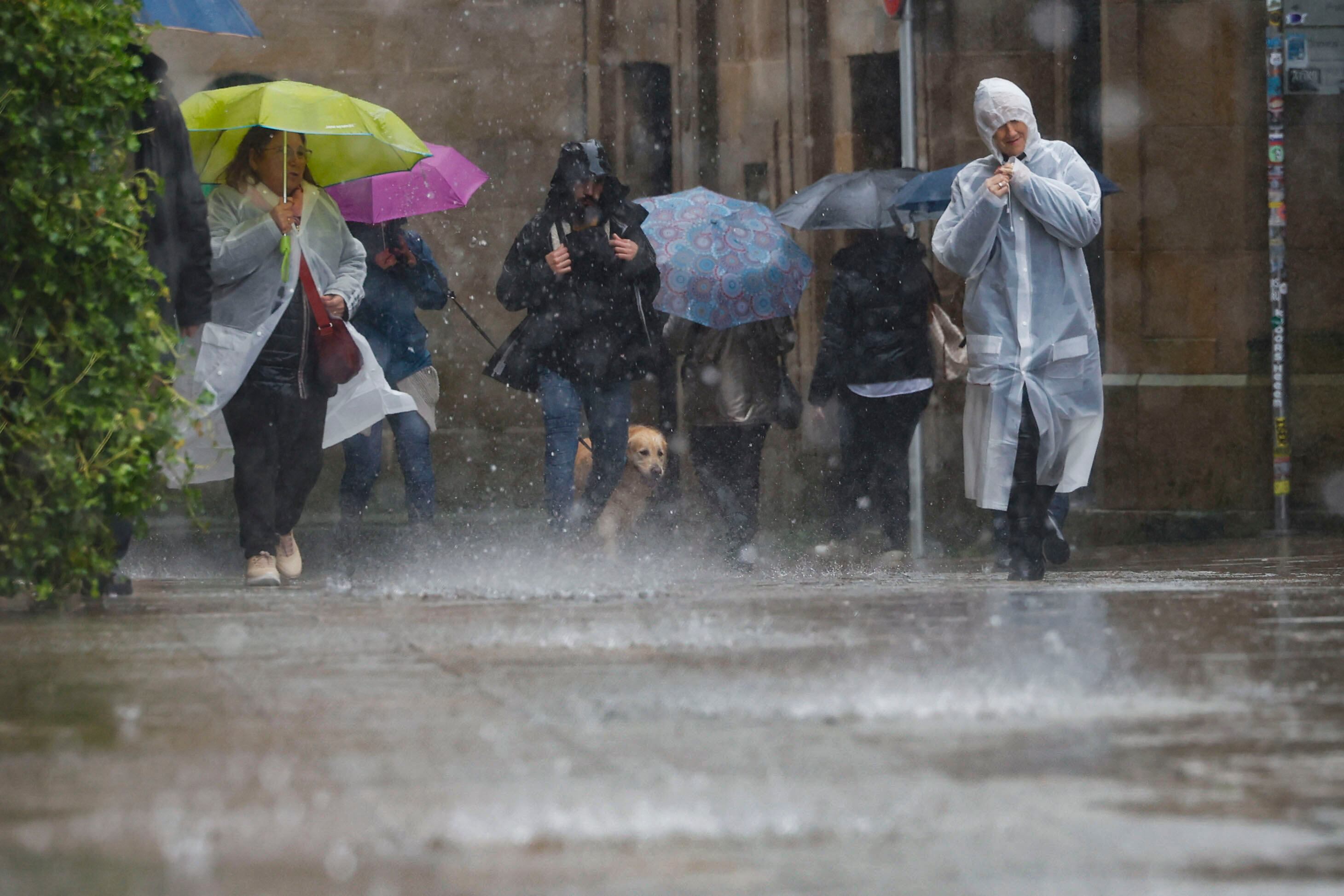 Varias personas con ropa para la lluvia en el casco histórico de Santiago de Compostela