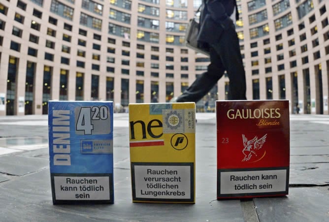 Un hombre pasa por delante de tres paquetes de cigarrillos expuestos frente al Parlamento Europeo (PE) en Estrasburgo (Francia)