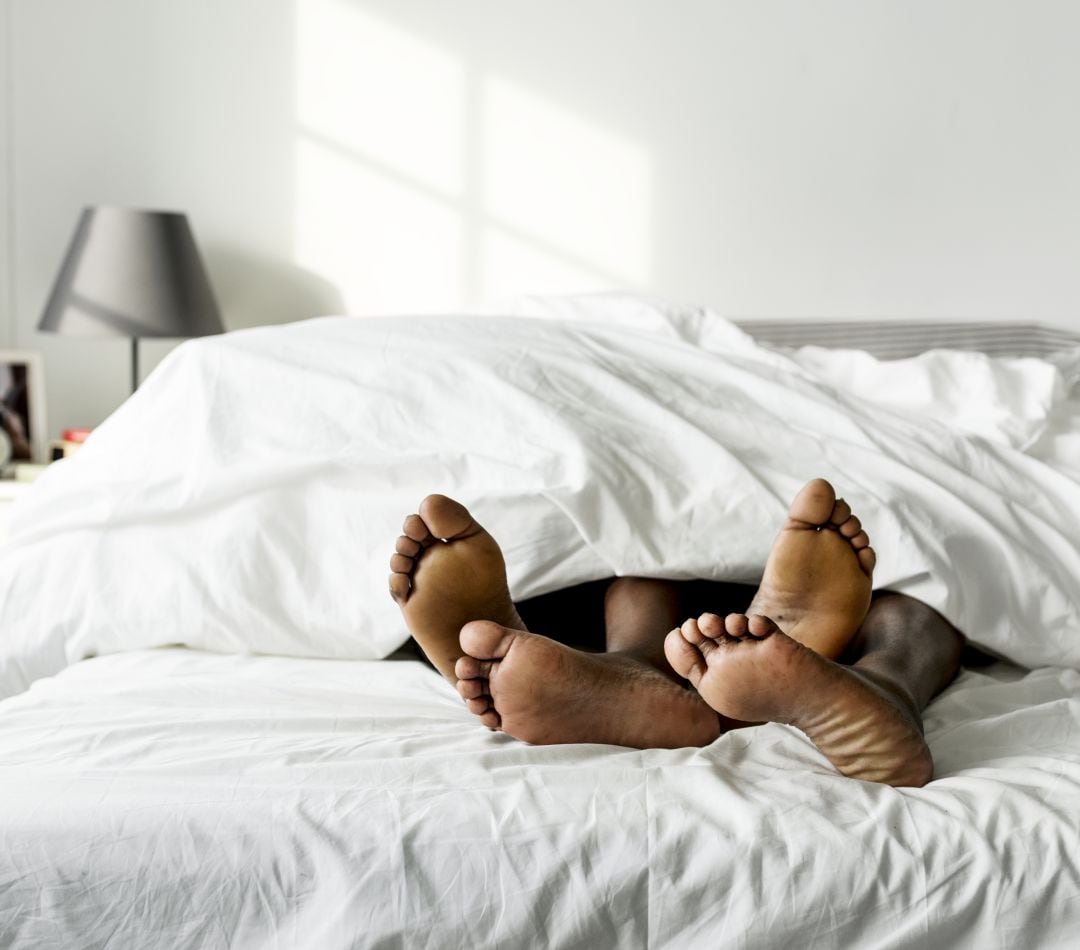 Una pareja enreda sus pies en la cama.