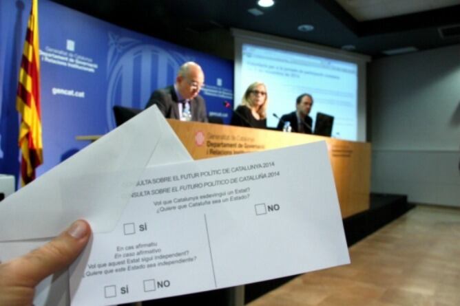 La papereta del procés participatiu del 9-N i un sobre de votació, davant la vicepresidenta del Govern, Joana Ortega