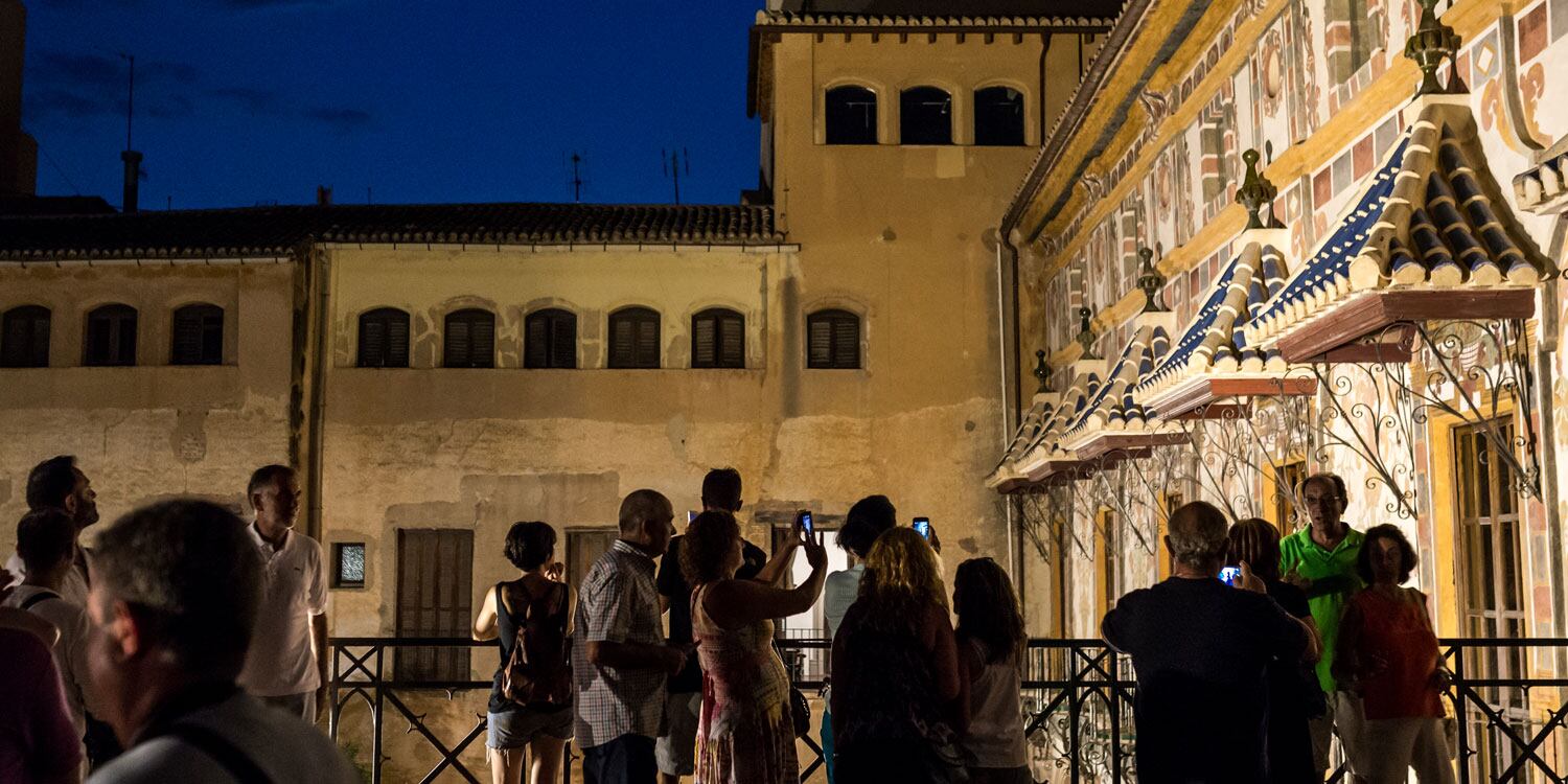 Unos turistas disfrutan de la visita nocturna del Palau Ducal de Gandia.