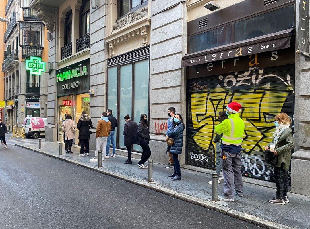 Varias personas hacen cola frente a una farmacia en Madrid para recoger las pruebas de antígenos de la Comunidad