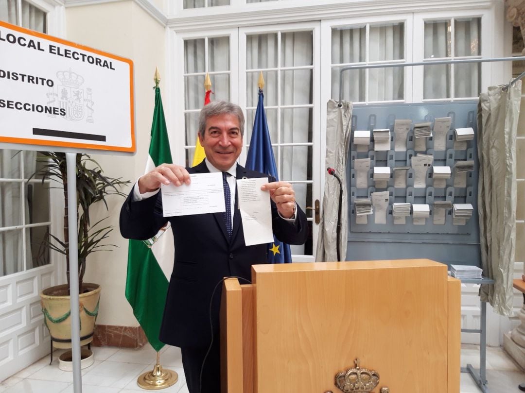 Lucrecio Fernández, delegado del Gobierno en Andalucía, enseña la diferencia de color de las papeletas realizadas en papel reciclado con respecto a un documento impreso en un folio