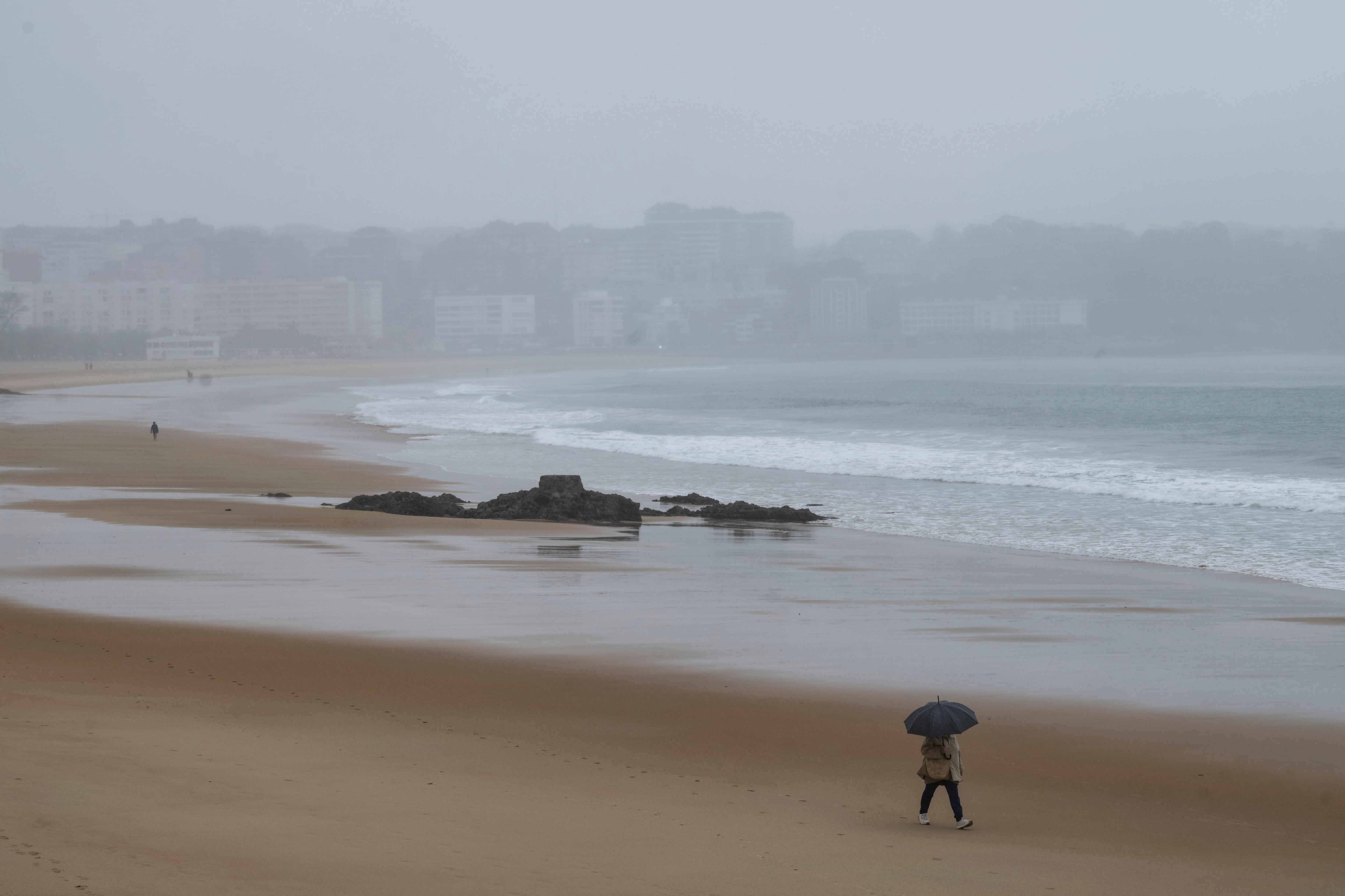 Una persona camina por la playa de El Sardinero este lunes en Santander. Cantabria esta en alerta amarilla, en el litoral y centro, por lluvia y fenómenos costeros adversos.