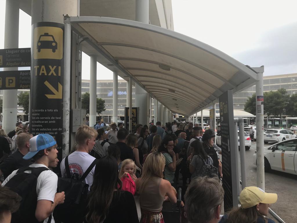 Turistas llegados a Palma hacen cola para tomar un taxi.