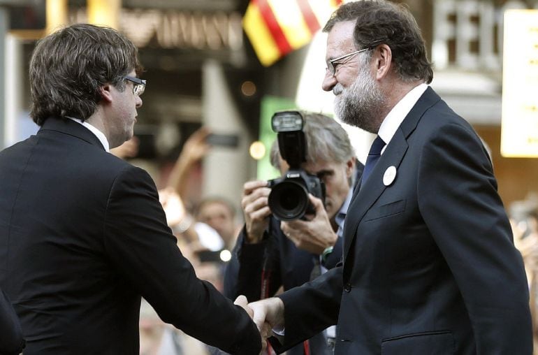 El presidente del Gobierno Mariano Rajoy (d) saluda al presidente catalán Carles Puigdemont (c) durante la manifestación contra los atentados yihadistas en Cataluña.