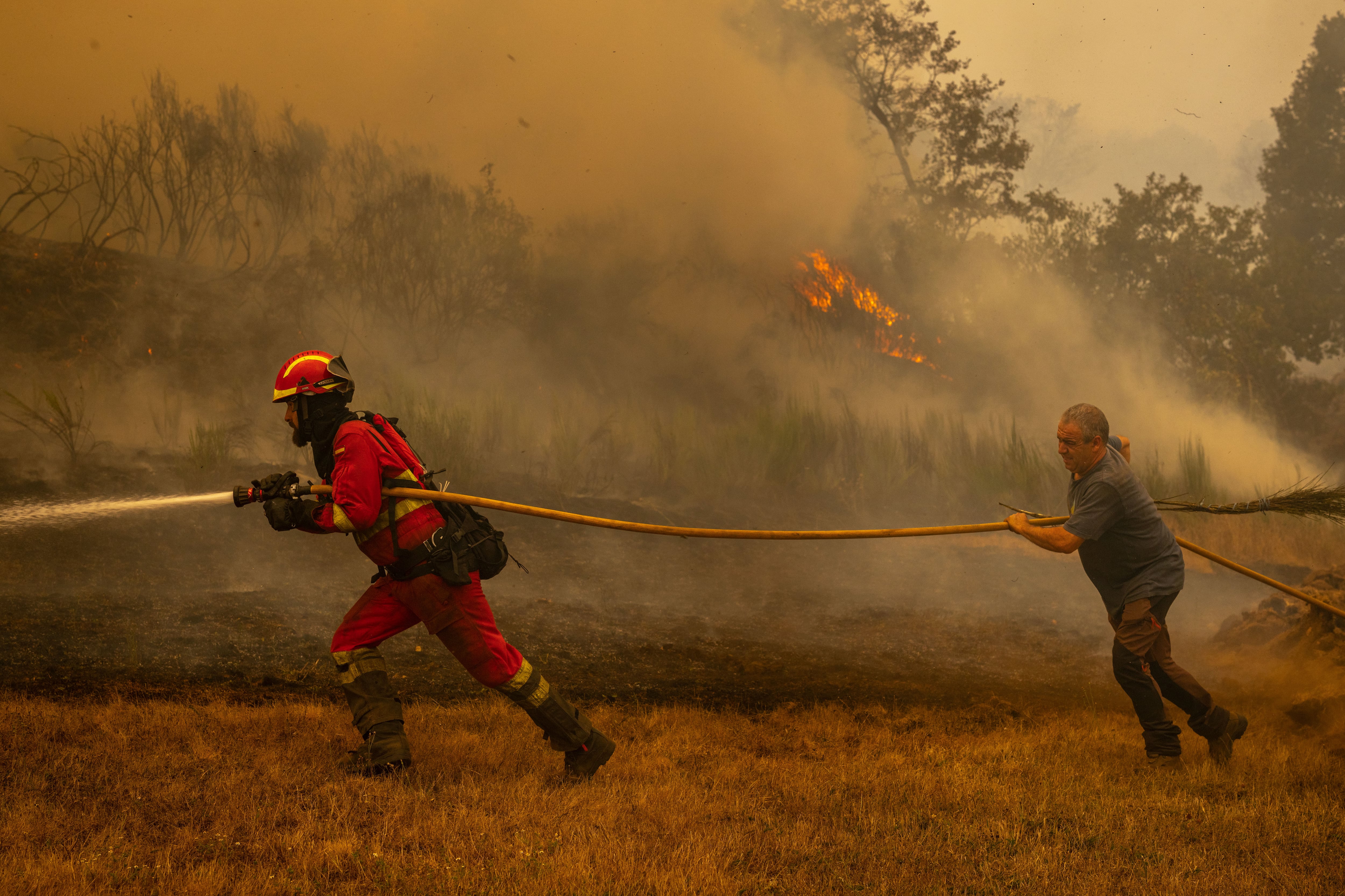 CHANDREXA DE QUEIXA (OURENSE), 12/08/2025.- Un efectivo de la Unidad Militar de Emergencias (UME) (i) en la localidad de A Espasa, durante el incendio forestal que permanece activo en Chandrexa de Queixa (Ourense), este martes. EFE/Brais Lorenzo
