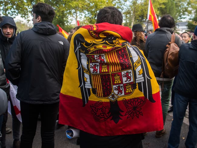 Un simpatizante del dictador Francisco Franco luce una bandera de la época preconstitucional durante una protesta cerca del cementerio de Mingorrubio.
