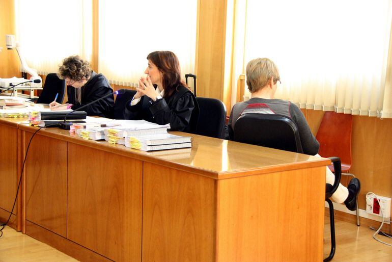 L'acusada, Remei Barrera, asseguda d'esquenes al costat de la seva advocada al banc dels acusats de l'Audiència de Tarragona