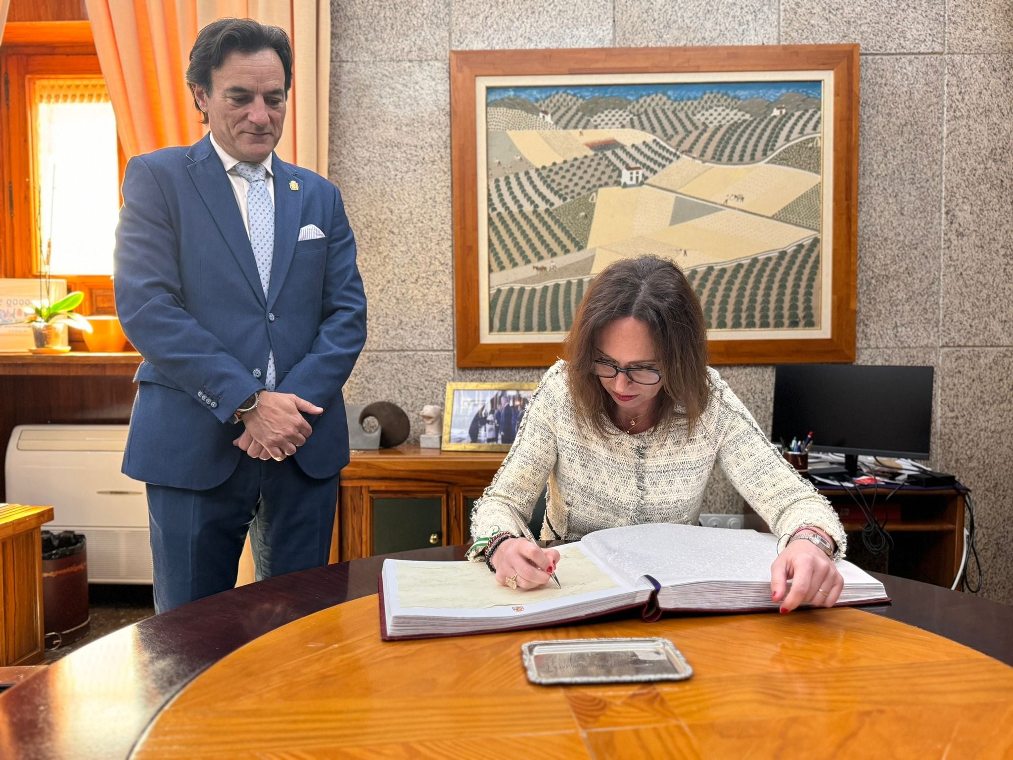 La consejera de Fomento, Rocío Díaz, firma en el Libro de Honor del Ayuntamiento en presencia del alcalde, Agustín González.